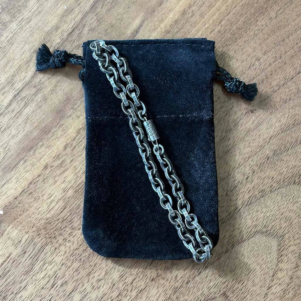 Silver chain necklace on a black velvet pouch on a wooden surface